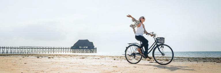 Junge Frau fährt mit ihrem Fahrrad an der Küste